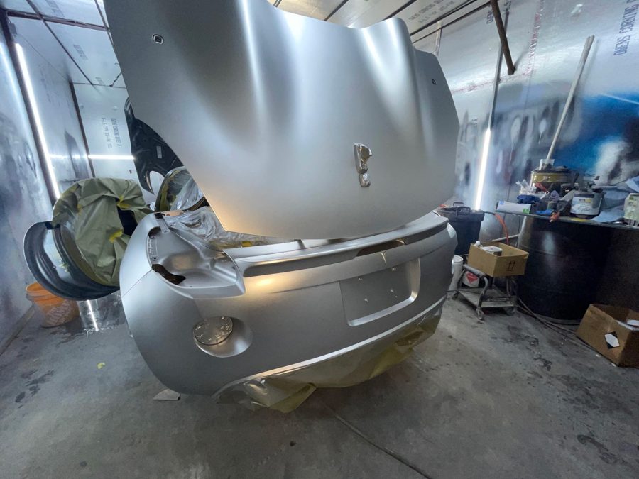 Vehicle in paint booth with hood up and bumper removed